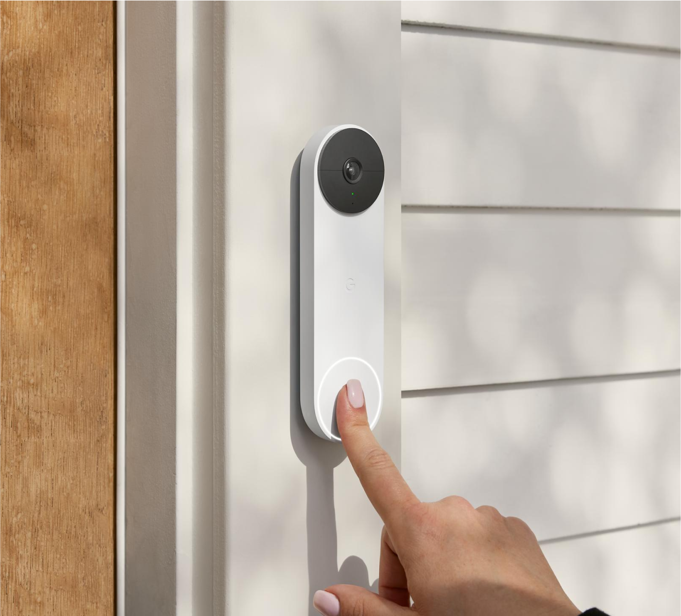 Finger ringing a Google Nest Doorbell on a doorframe outside a home