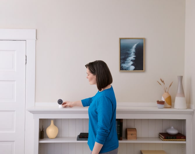 Woman adjusting an indoor camera in her home on a shelf