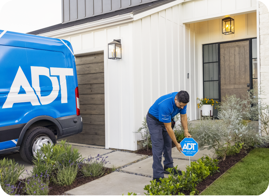 An ADT Tech Specialist putting an ADT sign at someone's house 