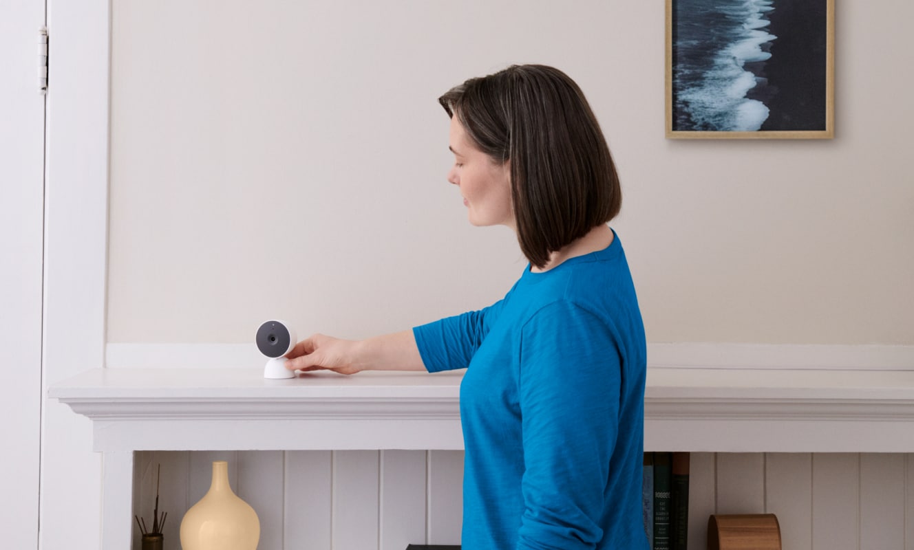 Woman adjusting an indoor camera in her home on a shelf