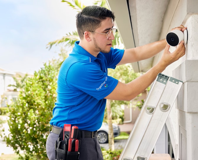 ADT installer putting a Google Nest Outdoor Camera on a house