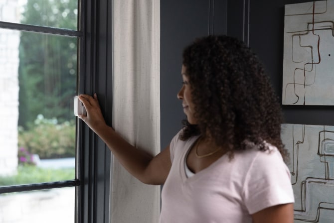 ADT customer placing a door/window sensor on her window