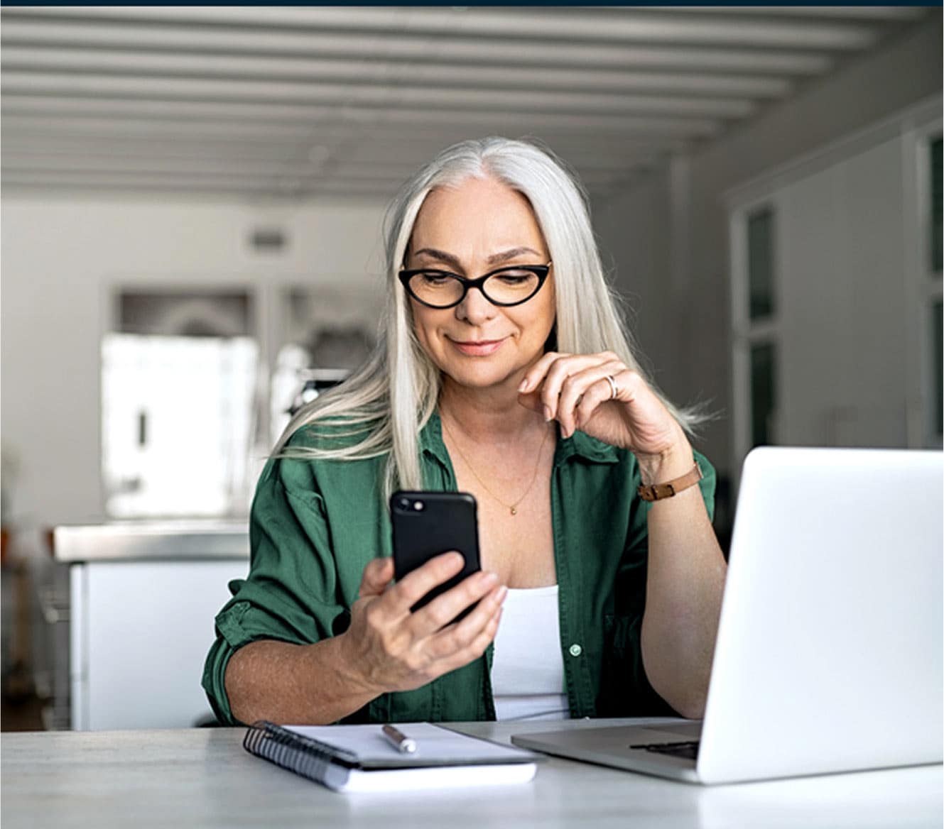 Woman looking at her ADT app on her phone in her home Woman looking at her ADT app on her phone in her home