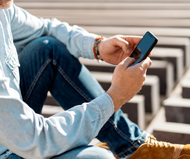 ADT sign on yard A person seated outdoors uses a smartphone, symbolizing remote control and monitoring of ADT business security systems.