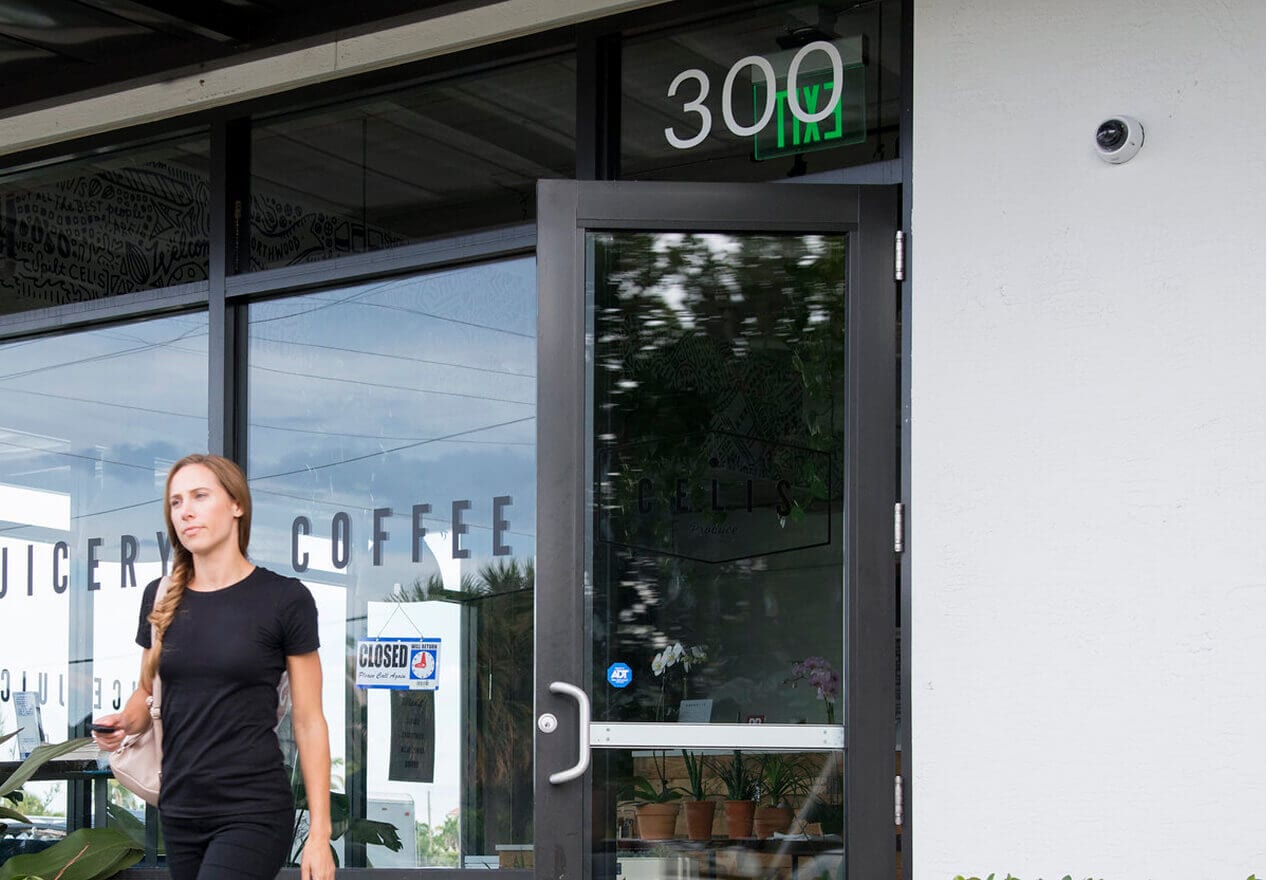 ADT Command Panel The front entrance of a business with a visible ADT security sticker and mounted surveillance camera.