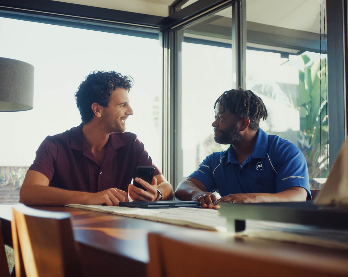 ADT bundle on shelf An ADT professional sits at a table with a homeowner, professional installation information together on a mobile device.