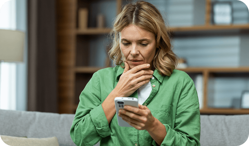 Concerned woman checking her phone Woman in green shirt looking concerned while using her smartphone.