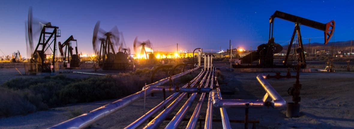 Field of oil pumpjacks and pipelines at twilight