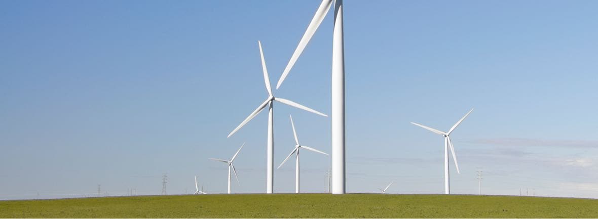 Wind turbines rising behind crest of a hill