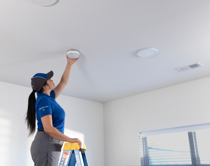 ADT installer installing a heat detector in someone's home