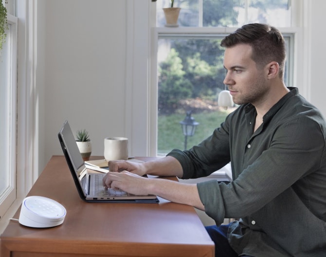 Man working on his laptop at a table with the ADT Keypad next to him Man working on his laptop at a table with the ADT Keypad next to him