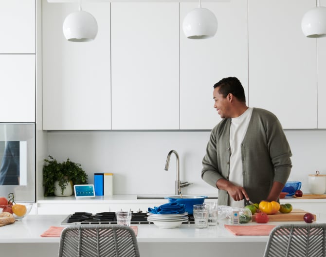 Hombre usando el control por voz con su Google Nest Hub, 2 generación, en la cocina