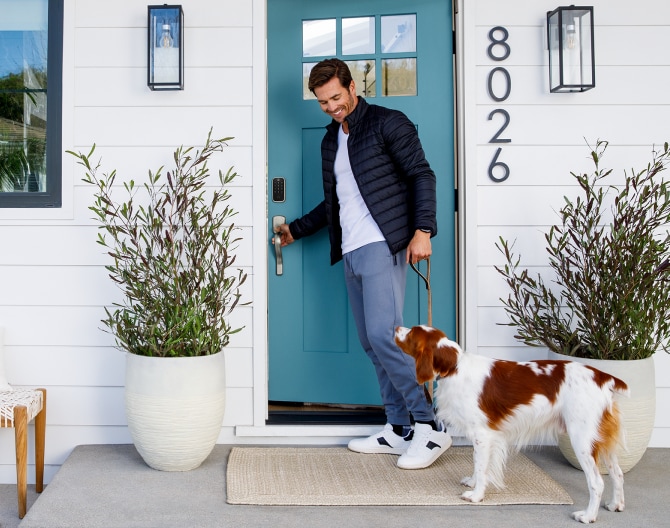 Homeowner with his dog outside of his front door that has a Yale Smart Lock on the door Homeowner with his dog outside of his front door that has a Yale Smart Lock on the door